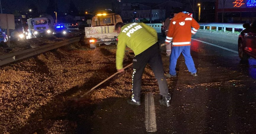 Polis eline aldığı fırçayla devrilen tırdan yola dökülen talaşı temizledi